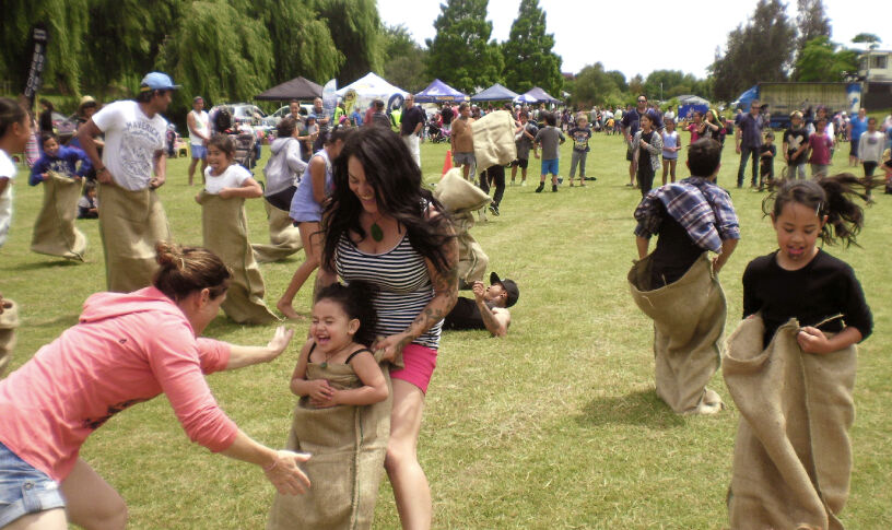 Image showing parents and kids playing sack race in a park